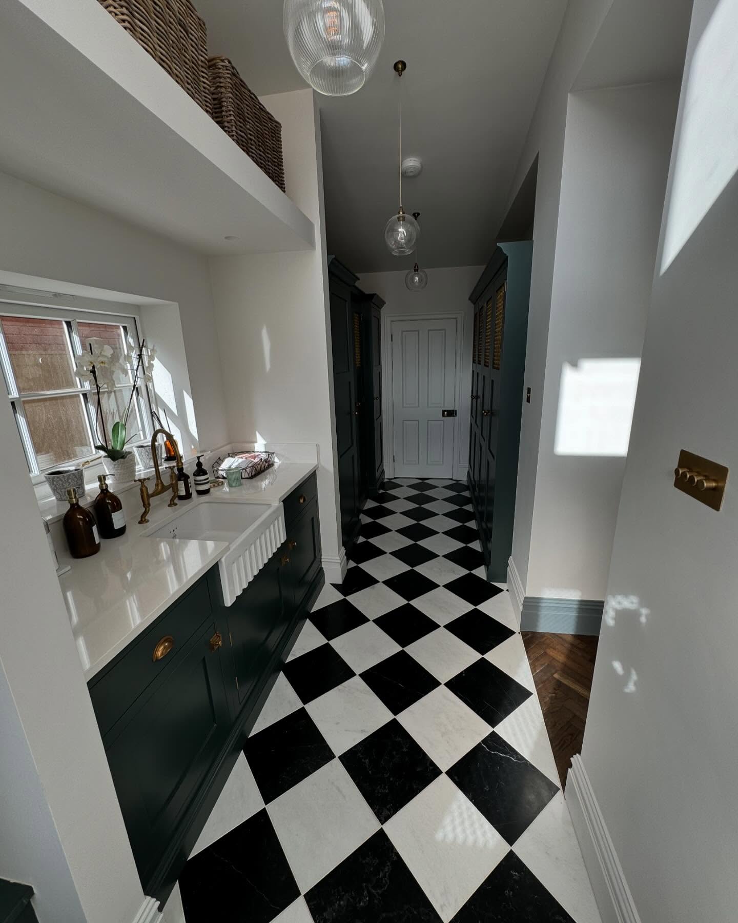 Utility hallway with a chequered floor and painted cabinetry